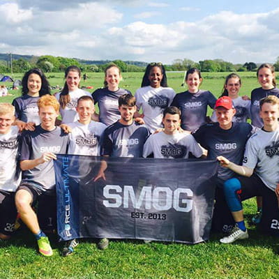 team poseren op grasveld met rokerige shirts en zwarte smogvlag