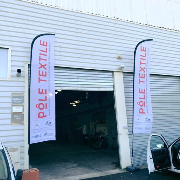 bâtiment industriel et deux oriflammes 'pôle textile'