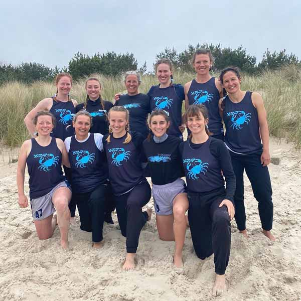 sportteam poseren op het strand, gekleed in rode tanktops