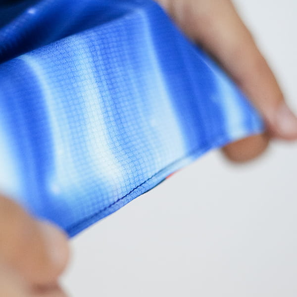 handen die blauwe gesublimeerde stof uitrekken