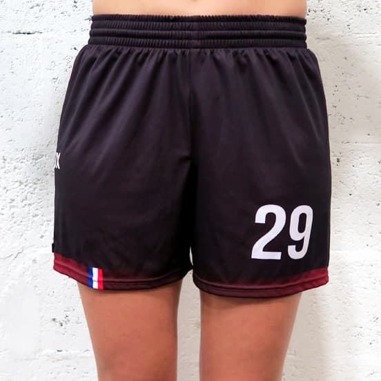 vue de face du bas du corps d'une femme portant un short noir féminin devant un mur blanc