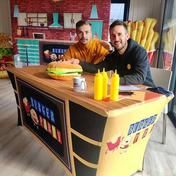 twee mannen aan een tafel in een kamer die een fastfood-omgeving nabootst